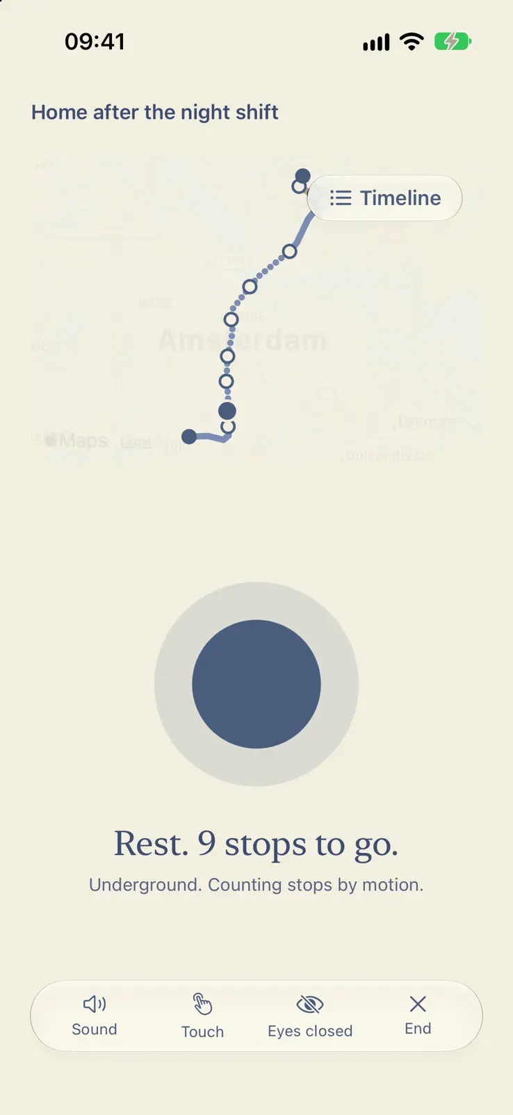 The ride in light mode, underground. The map has faded to the route line alone, over a navy orb in a pale ring. Rest. 9 stops to go. Underground. Counting stops by motion. A bar at the foot holds Sound, Touch, Eyes closed and End.